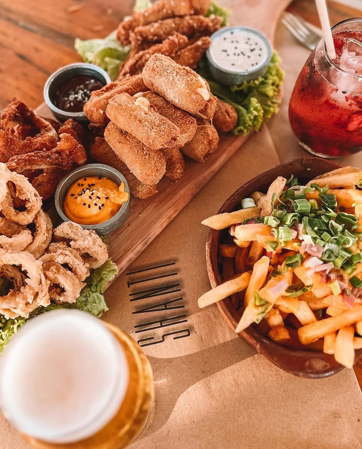 Fotografía gastronómica de SHANTI: bocados, papas y salsas sobre una mesa de madera.